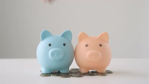 Two Piggy Bank Standing on Pile of Coins