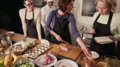 Koch beobachtet, wie eine Gruppe seiner Schüler während des Kochkurses Fleisch schneidet