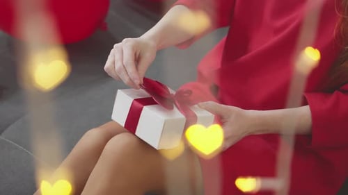 Woman in Red Dress Opening Gift with Red Bow