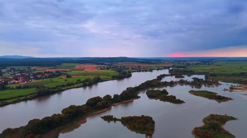 Aerial panorama of river bends and villages at sunset.