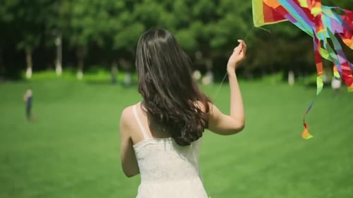 Woman Walks in Park Holding Colorful Kite
