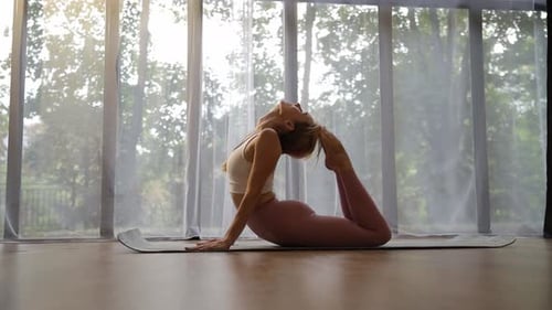 Woman Practicing Yoga on Mat in Sunny Studio