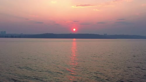 A Beautiful Big Sun Sets Outside the City on a Hill Near the Lake