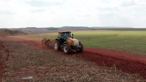 Vue aérienne de face basse du tracteur en train de travailler dur sur le terrain