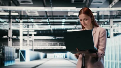Woman in Modern High Tech Server Hub Using Notebook to Do Maintenance