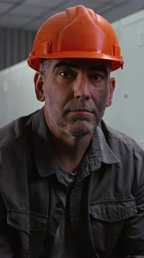 Mature Factory Worker with Serious Expression in Industrial Locker Room