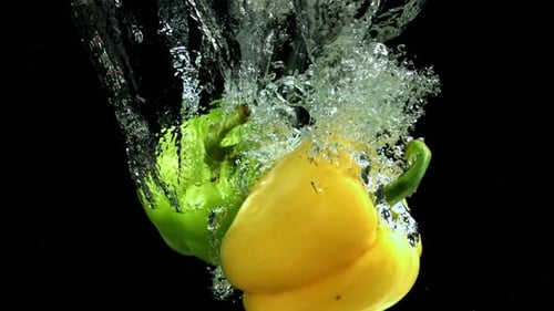 Mehrfarbige Paprika fallen unter Wasser, gefilmt mit einer Hochgeschwindigkeitskamera mit 1000 Bildern pro Sekunde
