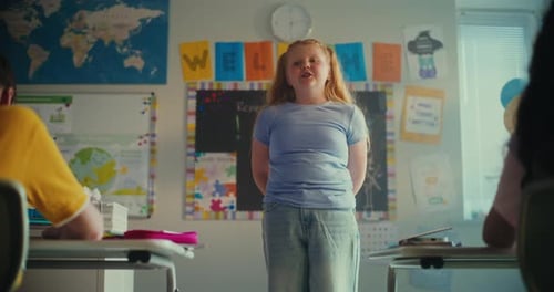 Shy Primary School Girl Showcasing Knowledge of Ecology in Front of Class and Teacher