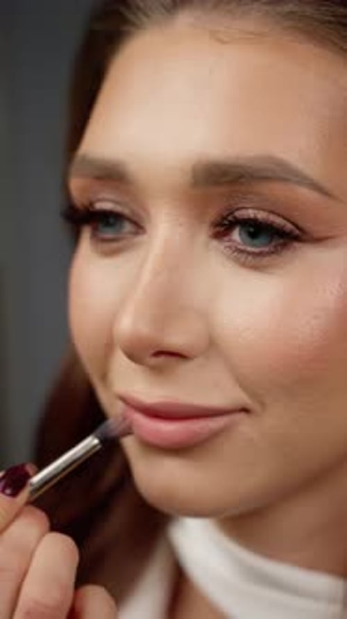 Professionelles Make-up: Lippenstift in leuchtendem Rosa mit feinem Pinsel zur präzisen Aufnahme von kosmetischen Details