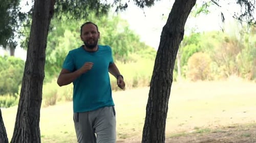 Handsome young man jogging in park super slow motion fitness training