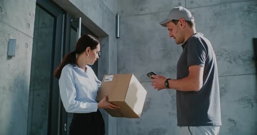 Businesswoman Taking Package From Postal Service Worker Signing POD on Smartphone