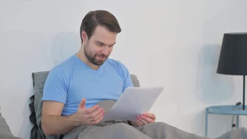 Man Reading Good News in Bed Celebrates Success