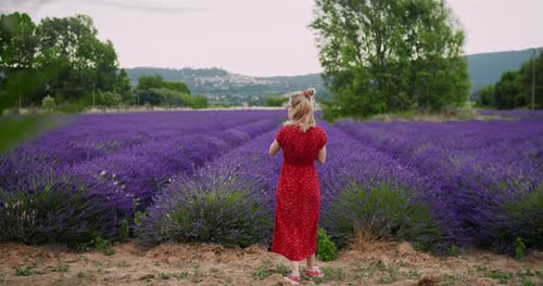 Belle femme blonde portant une robe rouge et faisant une photo d'un champ de lavande