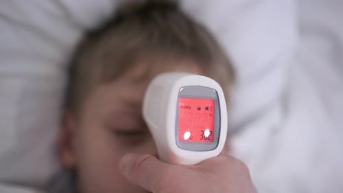 Doctor Measures Child's Temperature with Noncontact Thermometer