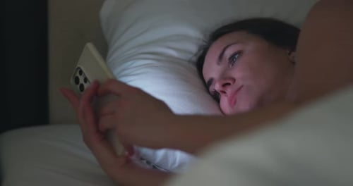 Woman Using Smartphone in Bed at Night