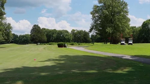 Sunny Day at Golf Course Greens with Golf Carts Sitting in Background