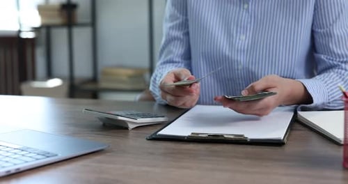 Counting Money on Desk with Laptop and Calculator
