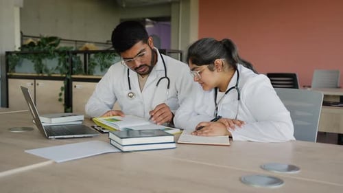 Indian Medical Students Studying with Books and Laptop in Library