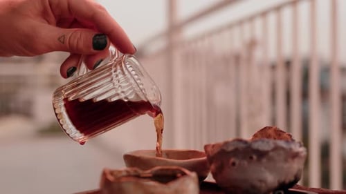 Side View Pouring Tea From Transparent Milk Jug Into Cup