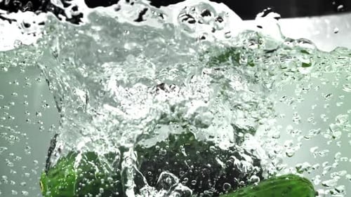 Green Cucumbers Splashing Refreshingly into Water