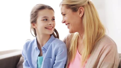 A happy mother and daughter share a sweet smiling moment at home together