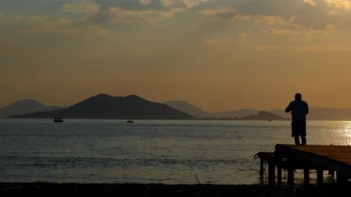 Man Fishing on Dock at Colorful Sunrise