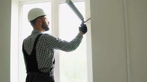 Construction Worker Sealing Window Frame with Foam Sealant