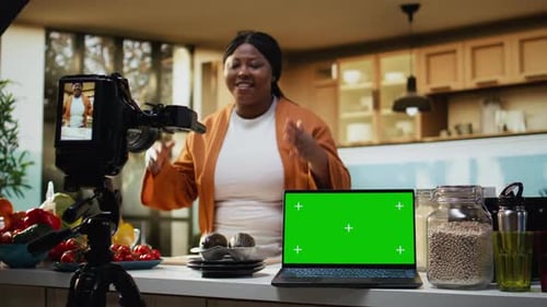 Pantalla verde aislada en una computadora portátil junto a una mujer cocinando en el mostrador