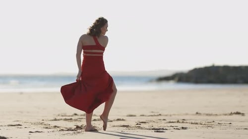 Graceful Young Woman in Red Dress Dancing on the Beach