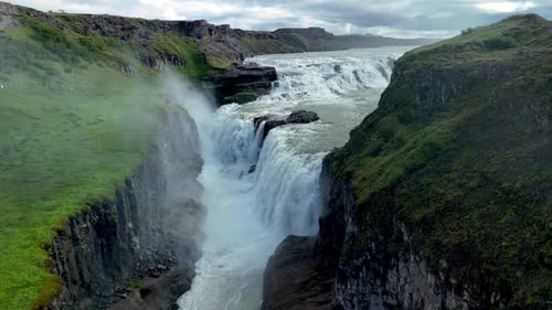Majestic Waterfall Cascading Through Icelandic Landscape Under Cloudy Skies Near Gullfoss