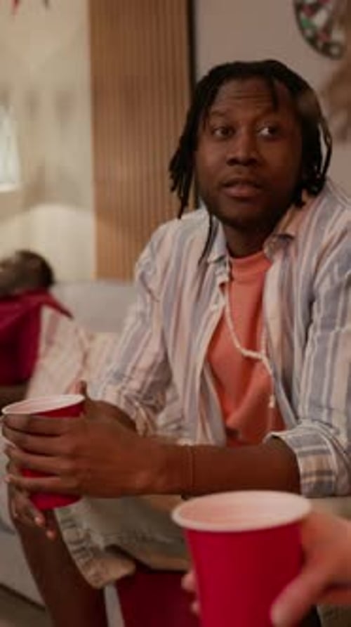 Vertical of Black Man Holding Cup and Telling Story to Friends at Party