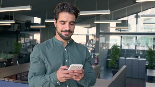Happy Latin Business Man Executive Employee Using Cell Phone Standing in Office