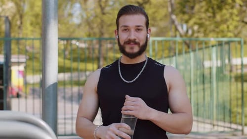 Athletic Man Drinking Water in Urban Park