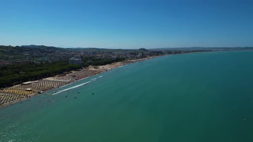 Adriatic coastline in Durres, Albania with beach surrounded by green pines, hotels, and resorts for