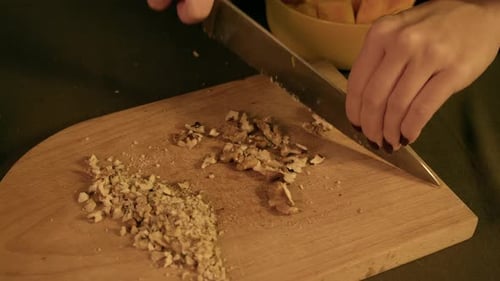 Woman Chopping Walnuts on Wooden Cutting Board