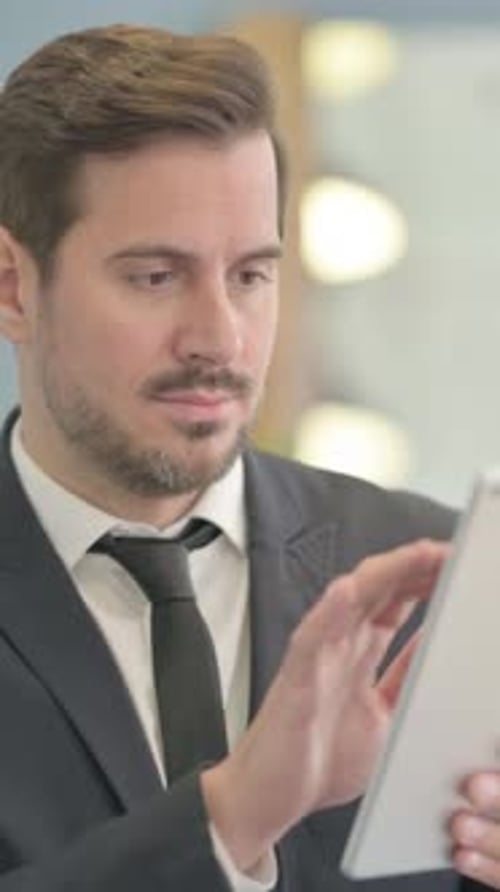 Concentrated Businessman Works on a Tablet Device