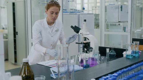 Female Scientist Working With Microscope in Bright Lab