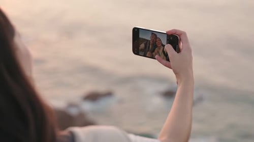 Couple Taking Selfie By Ocean at Sunset with Smartphone