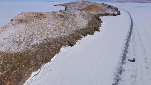 An Aerial View Shows a Snowcovered Island Terrain with a Road Passing Through a Winter Landscape