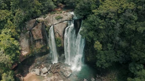 Majestic Aerial View of Tropical Waterfall Cascading Down Rocky Cliffs