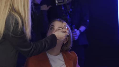 Crew Preparing for Shoot in Studio A Woman Make Up Artist Applies Powder to the Face of a TV