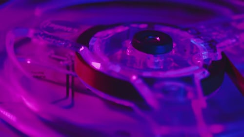 Closeup of a Transparent Reel Rotating on a Vintage Analog Tape Recorder Bobbin with Retro Tape in