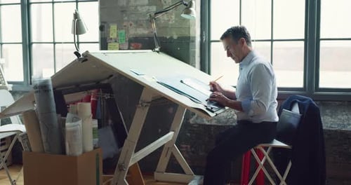 Architect at drafting table creates architectural sketches in office space