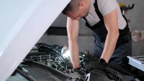 Mechanic Working on Car Engine in Garage Workshop Concept of Car Service and Car Maintenance