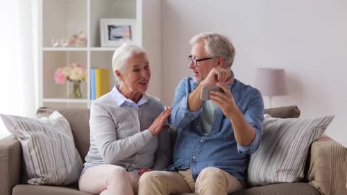 Senior couple uses phone together in their living room