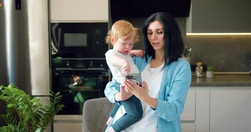 Mother and Child Using Smartphone in Modern Kitchen