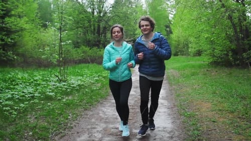 Sportive young people running. Couple run in the park during rainy day