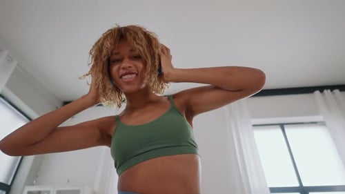 Young Woman Dancing with Headphones in Bright Room