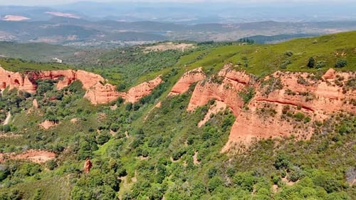 Orange rock formations with greenery on the slopes. Sunny view of the mountainous landscape
