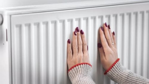 Woman Warming Hands on Radiator